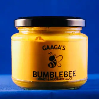 Bottle of Bumblebee Honey & Mustard with a spoonful drizzled over roasted chicken and vegetables