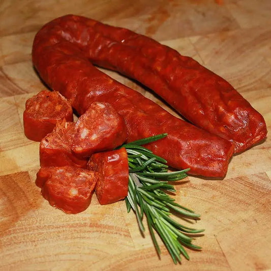 Chorizo links browned and sizzling in a pan, sliced to show the deep red paprika-rich