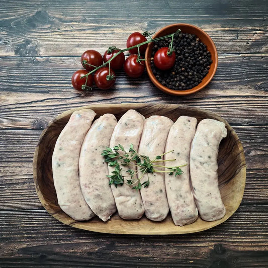 Cumberland sausages browned in a pan—peppery, coarse-ground links served with mash and onion gravy