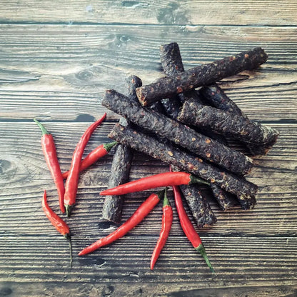 Droëwors chilli—thin sticks of air-dried beef sausage with a clean snap and gentle chilli heat, served on a snack board