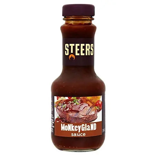 Bottle of Monkey Gland sauce beside a grilled steak and boerewors roll, with a glossy, tangy glaze